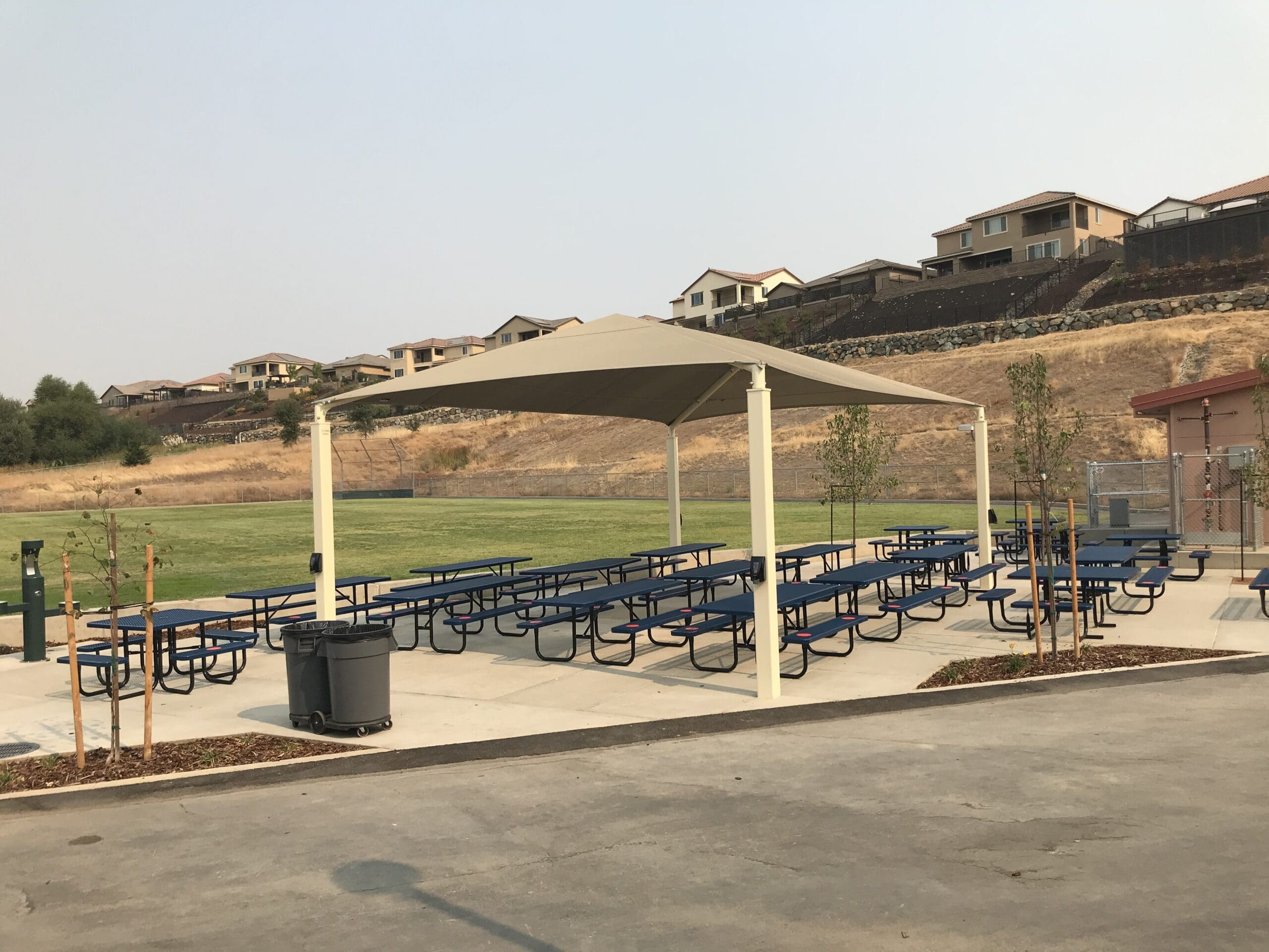 park picnic tables covered by tan sun shade