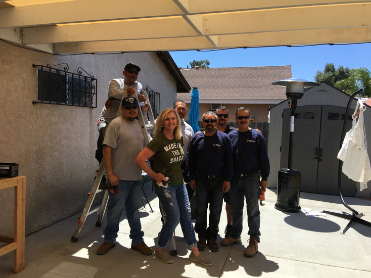 Patti Abrecht stands under the new shade with the Orange County installation crew.