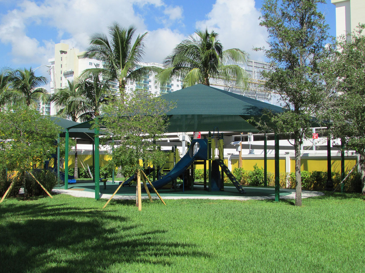 green shade covering playground surrounded by trees