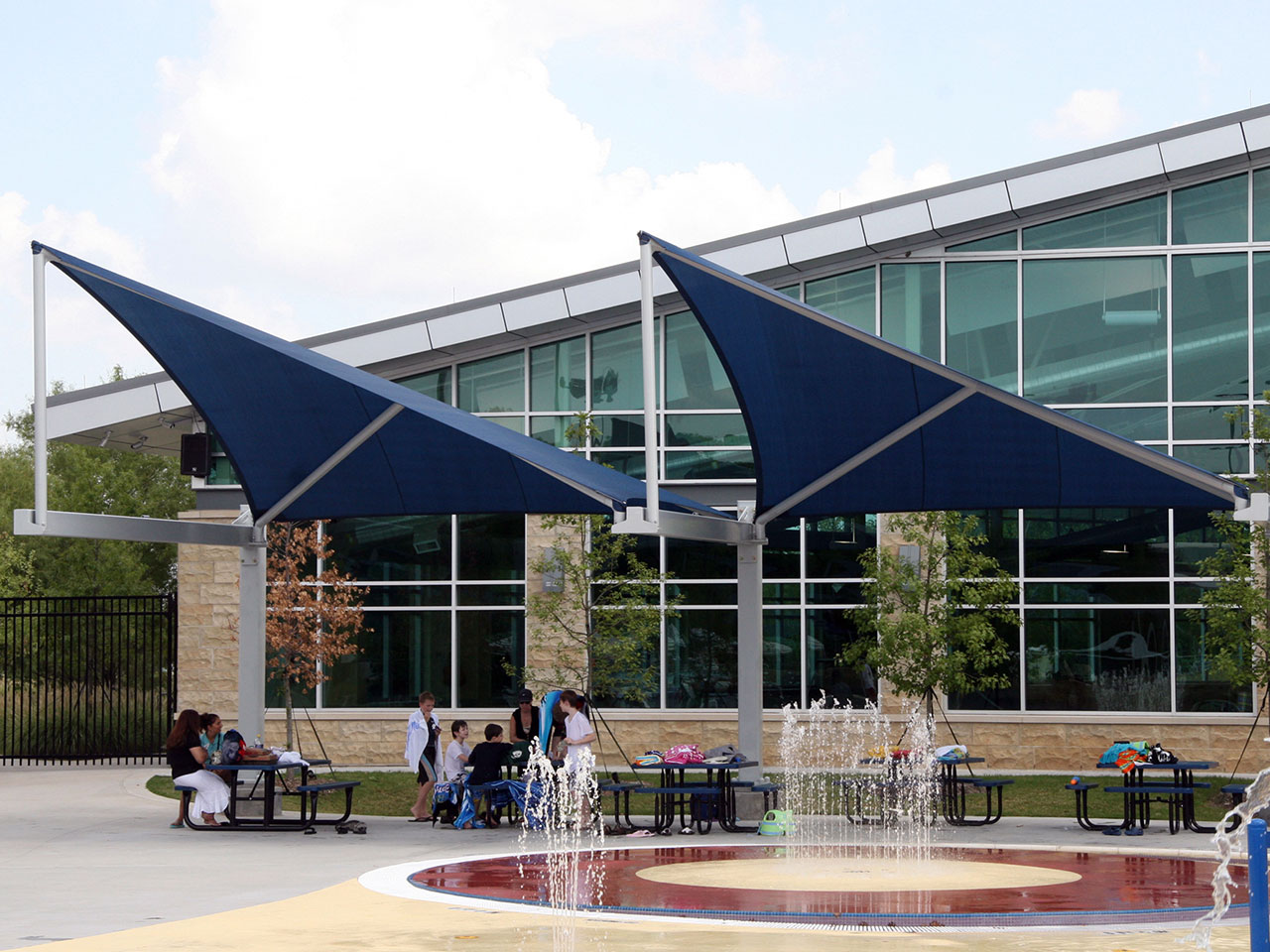 people sitting at outdoor tables covered by usa shades