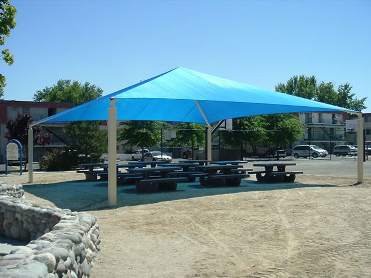 outdoor picnic tables underneath blue usa shade
