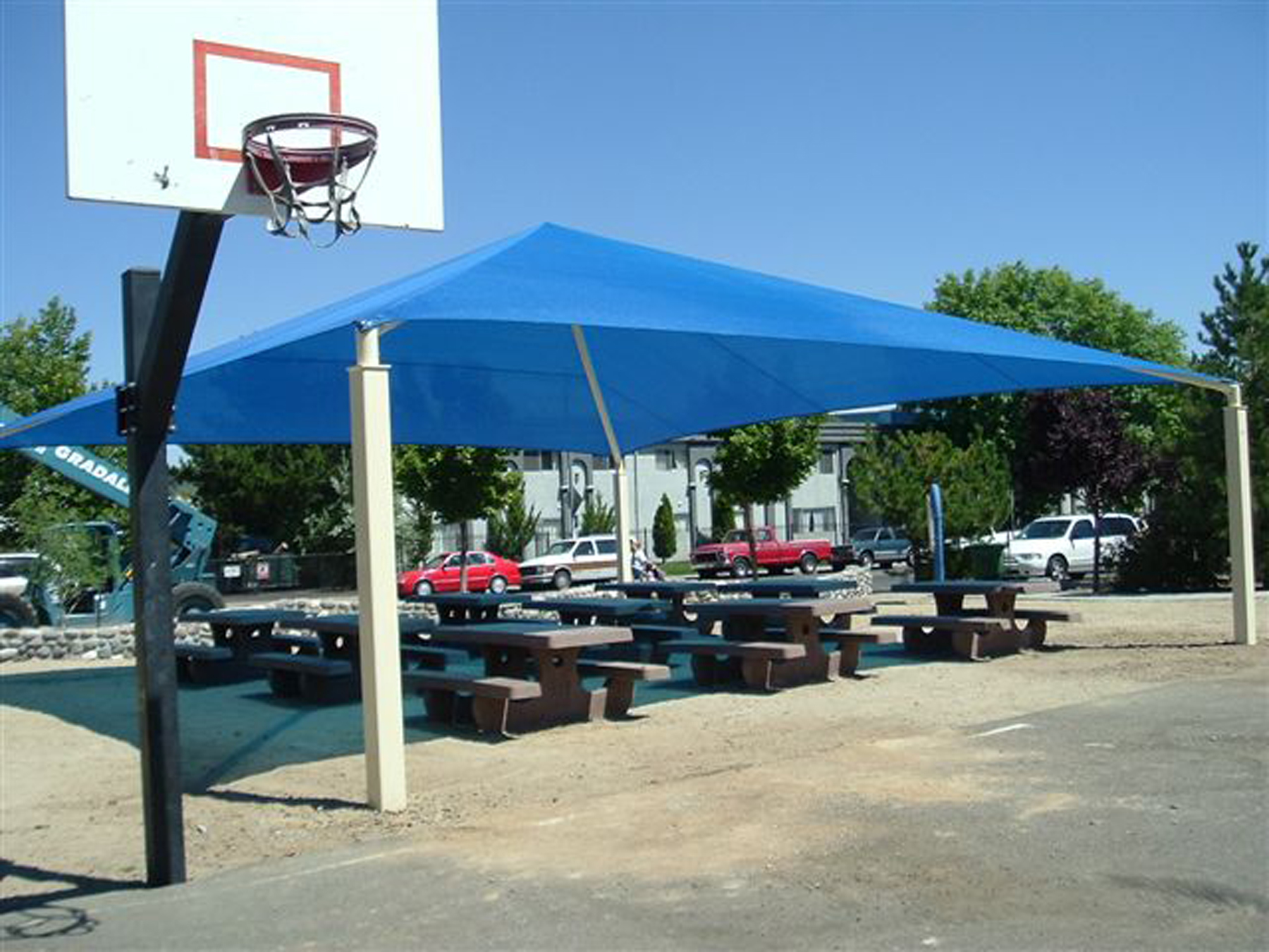 park picnic tables underneath blue sun shade