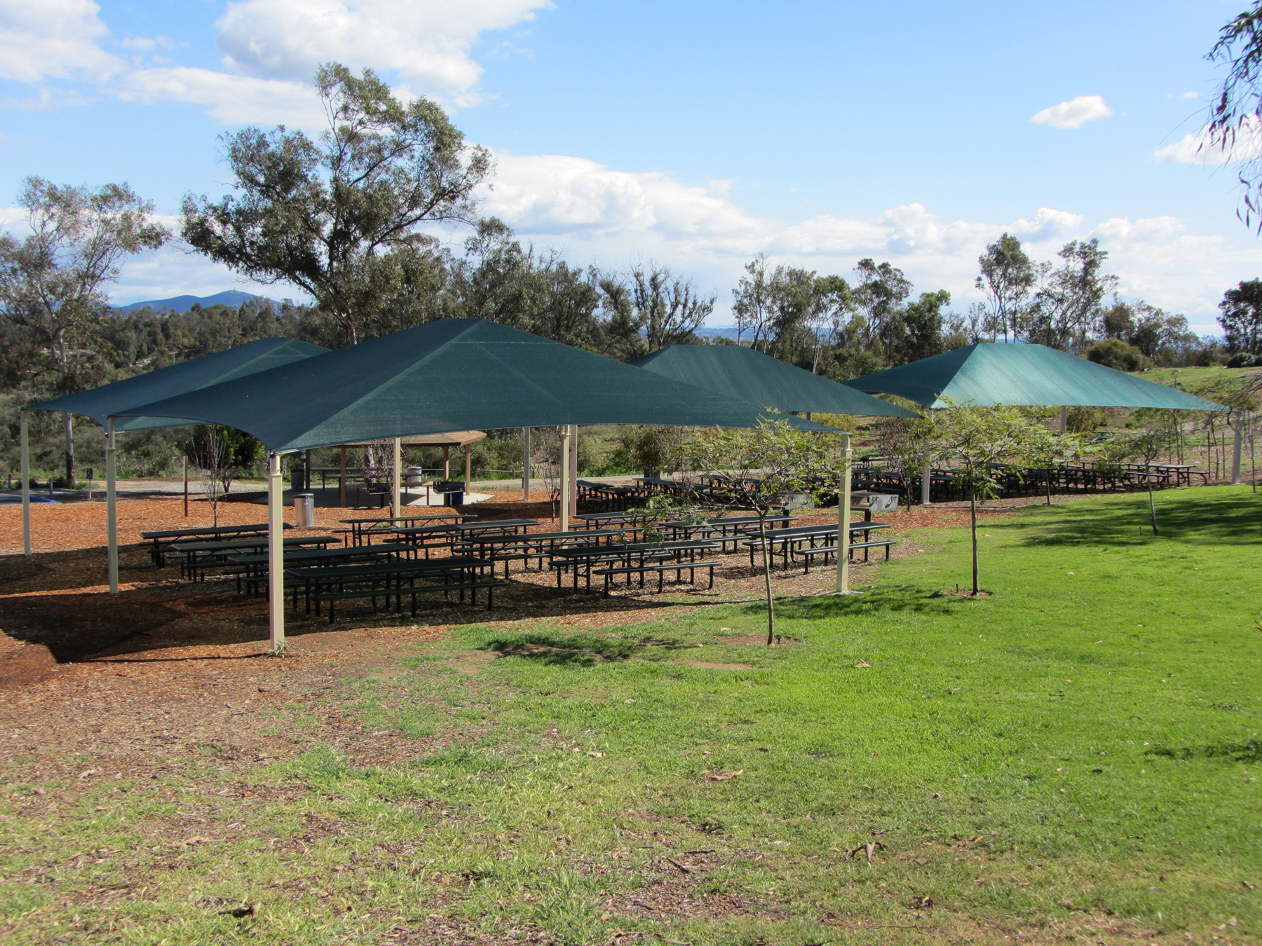 picnic tables outside under sun shades