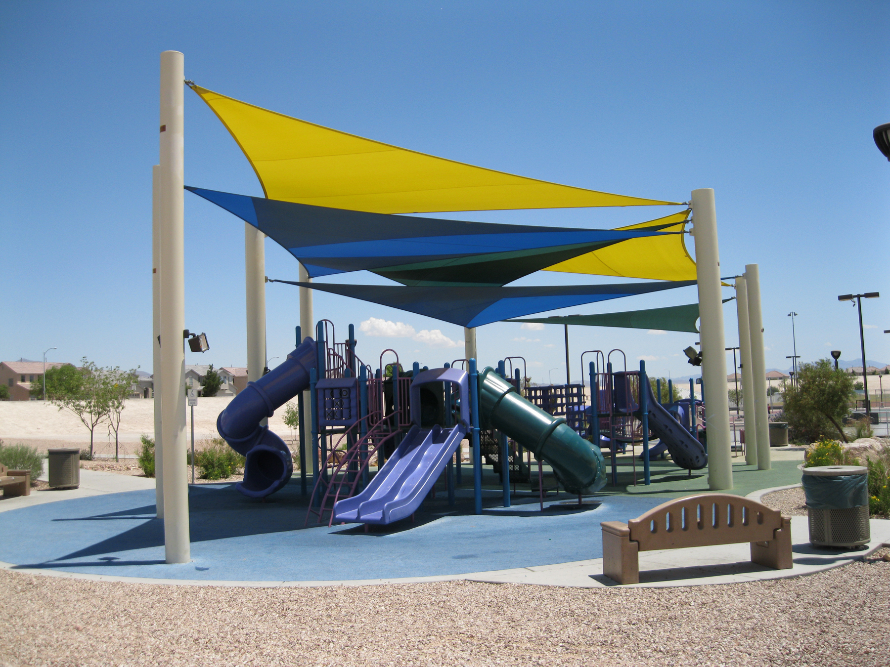 A 3 point sail sun shade over top of a playground.