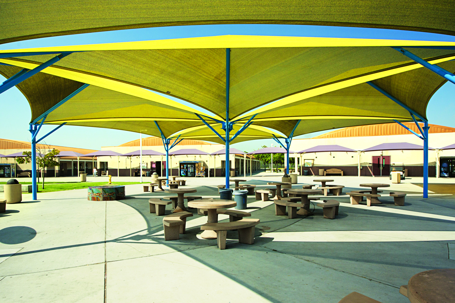 outdoor picnic tables underneath yellow usa shade