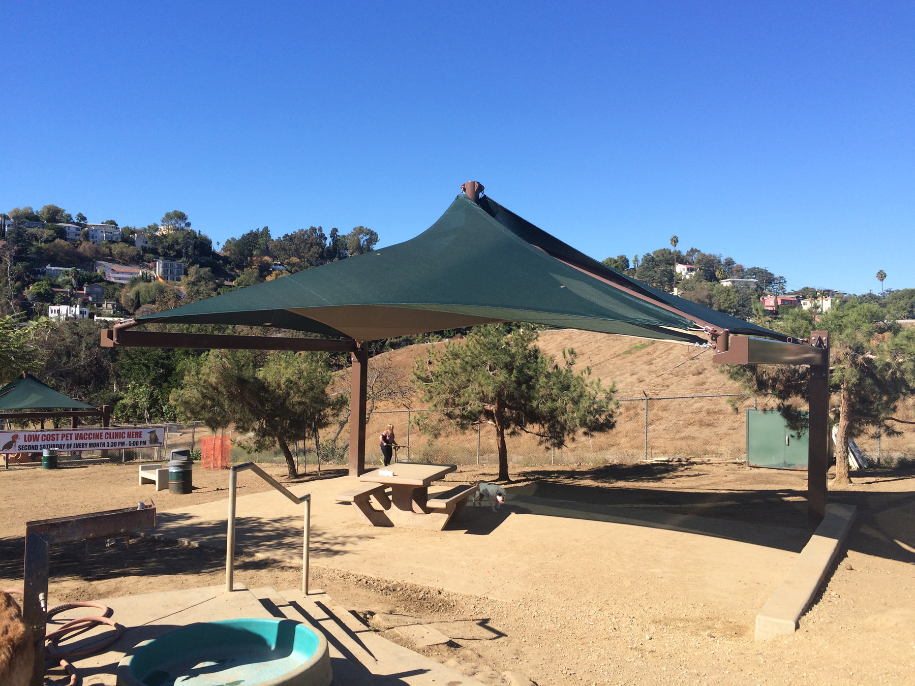 green sun shade covering seating at dog park