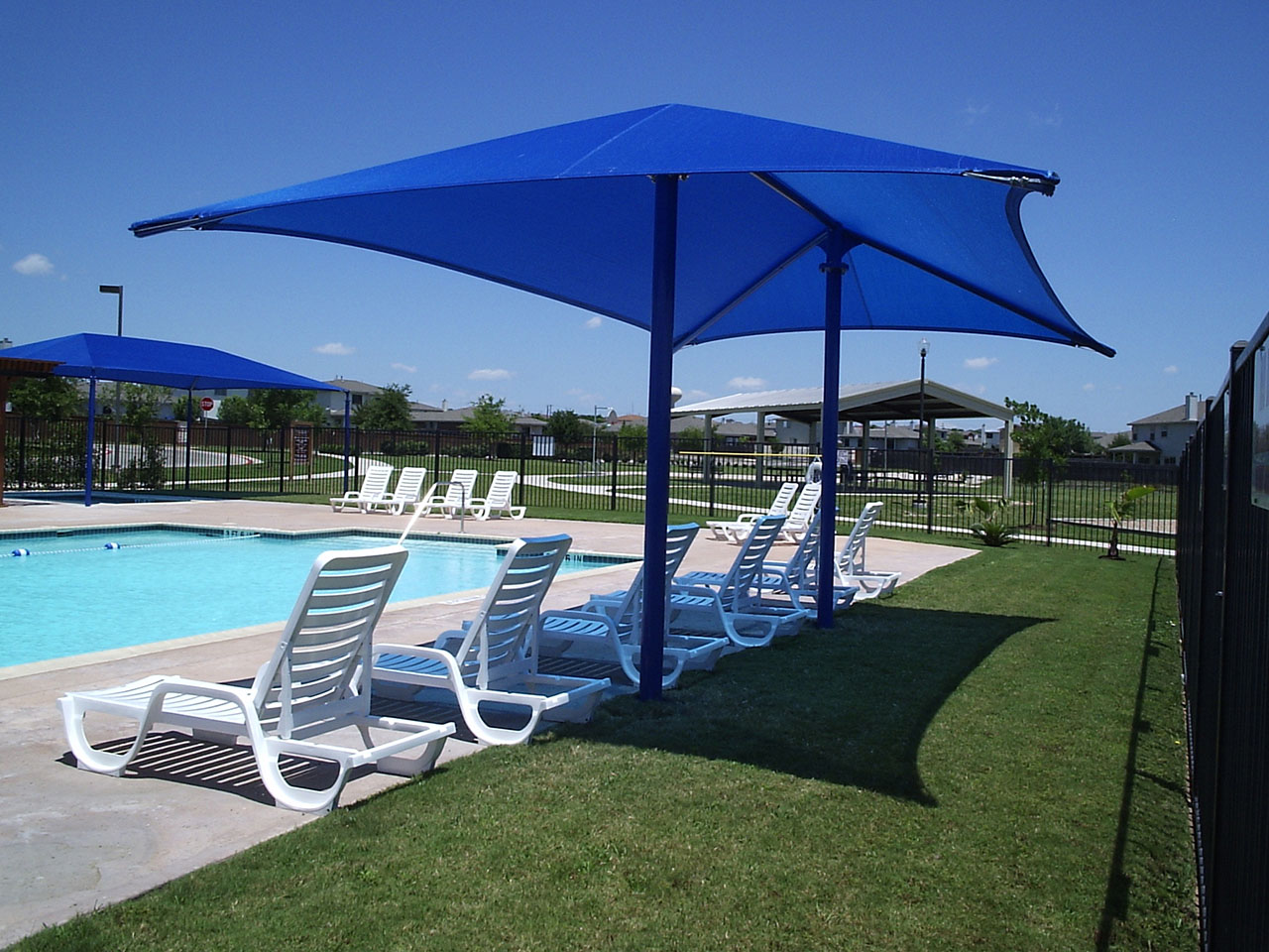 blue shade covering lawn chairs by pool
