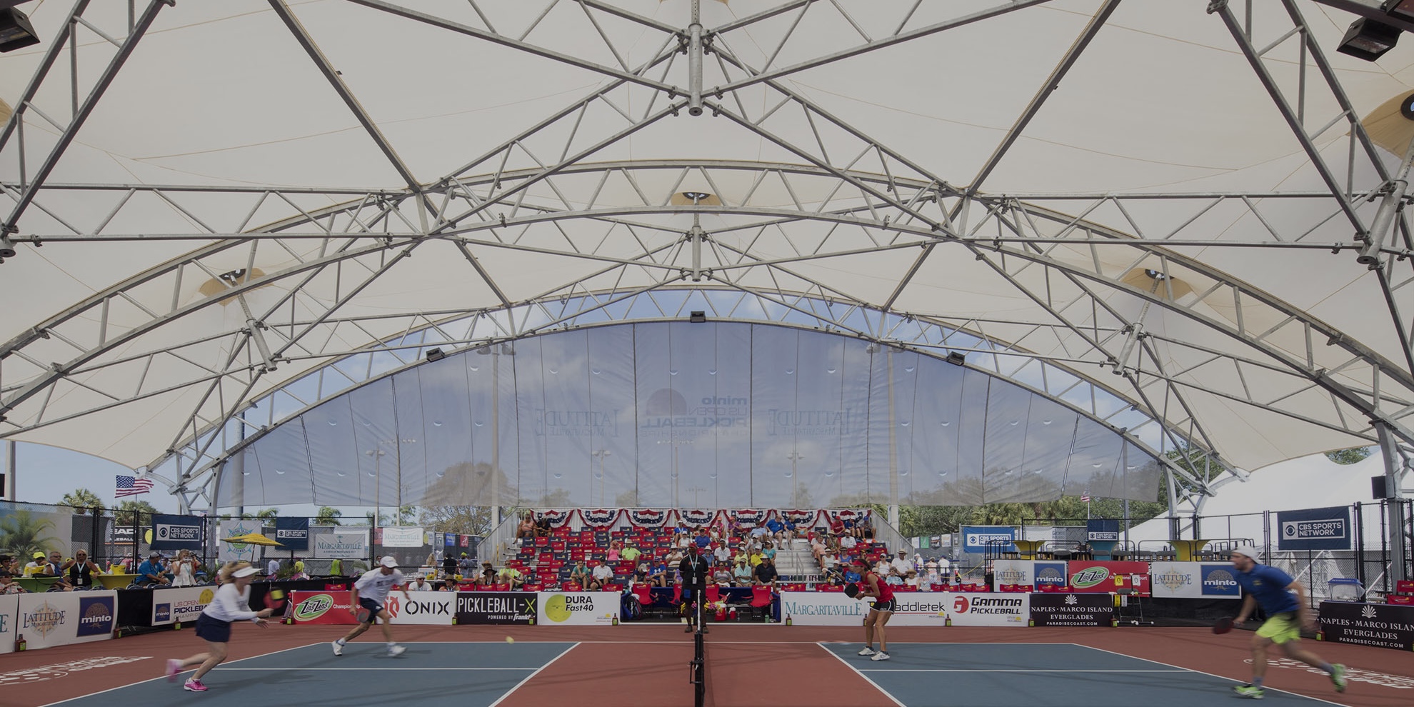 pickleball courts, people playing pickleball, courts protected from sun by shade covering